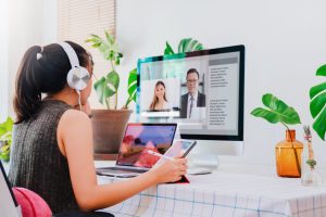 A scene depicting the girl actively participating in a virtual team meeting, with colleagues visible on the computer screen, showcasing a collaborative work environment.